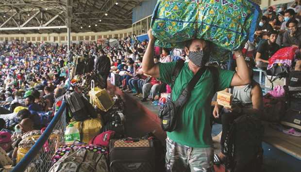 A man carrying a bag of belongings walks inside the baseball stadium where thousands of stranded Filipinos due to the coronavirus disease (Covid-19) restrictions are crammed while waiting to be transported back to their provinces, in Rizal Memorial Sports Complex, Manila, yesterday.