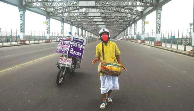 An unemployed musician sings and dances with his drum to create awareness about the spread of the Covid-19 on the Howrah Bridge during a complete lockdown announced by the state government, in Kolkata yesterday.