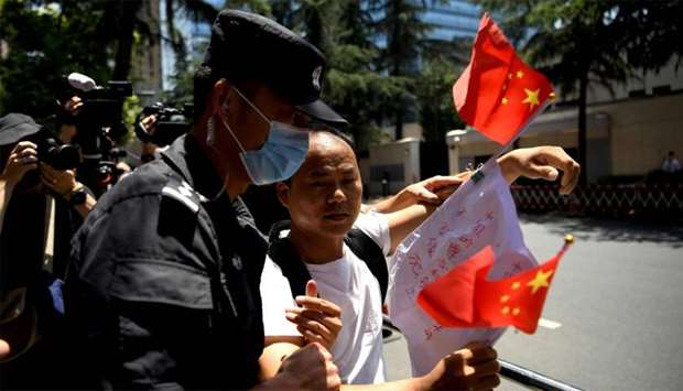 A man holds a banner and shouts u201cChinese government is greatu201d is escourted by policemen in front of the US Consulate in Chengdu, southwestern China's Sichuan province