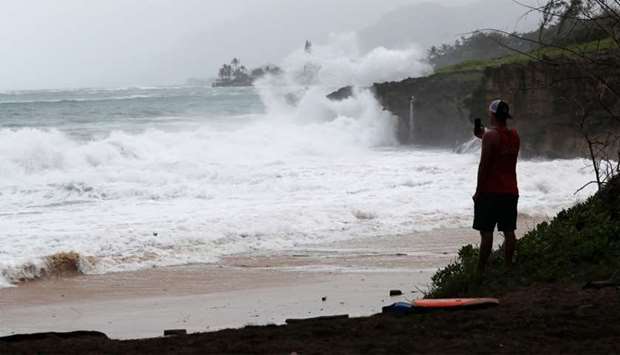 A beach goer watches the big waves wash up on Pounder's Beach in Laie, Hawaii as Hurricane Douglas makes its way towards Oahu