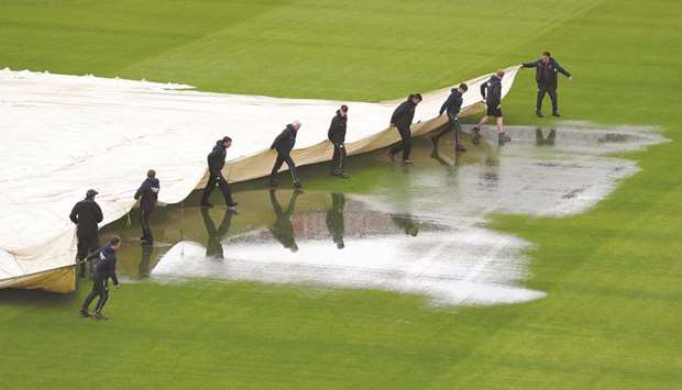 Groundstaff hold a pitch cover at Old Trafford yesterday. (Reuters)