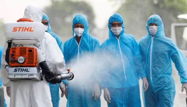 A health worker in a white protective suit sprays disinfectant at Vietnamese construction workers infected with the coronavirus disease, upon their arrival at the tropical diseases hospital after being repatriated from Equatorial Guinea via a specially-adapted Vietnam Airlines plane filled with medical equipment and negative pressure chambers, in Hanoi.