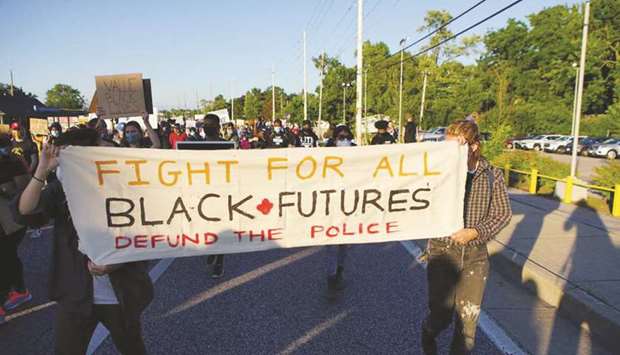 Protesters carry a banner calling to defund the police, during a protest against police brutality of a man hit by a Florissant detective and the death in Minneapolis police custody of George Floyd, in Florissant, Missouri, US.
