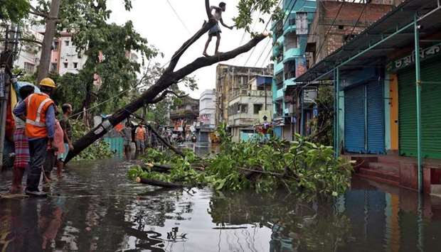 A man cuts branches of an uprooted tree after Cyclone Amphan made its landfall, in Kolkata, India, in this May 21, 2020, photograph.
