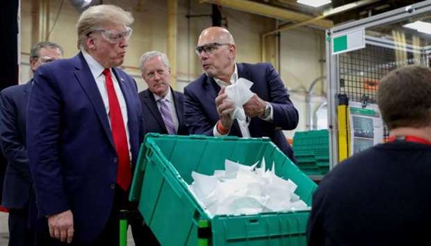 FILE PHOTO: US President Donald Trump looks at a face mask being shown to him by Honeywellu2019s Vice-President of Integrated Supply Chain Tony Stallings, on May 5, 2020.