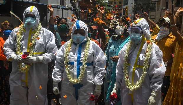 People shower flower petals to honour state health workers who came to collect swab samples from people testing for coronavirus in Kolkata.
