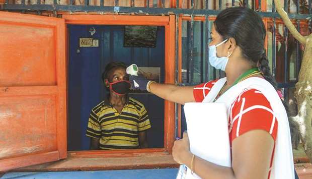 A health worker checks the body temperature of a man at a containment zone in Chennai yesterday.