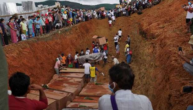 Volunteers bury bodies of miners in a mass grave while relatives look on during a funeral ceremony near Hpakant in Kachin state