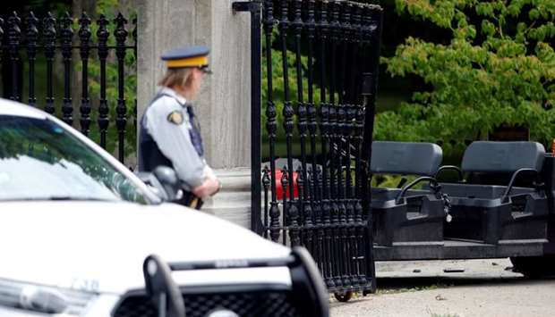 A police officer looks at the damaged gate at Rideau Hall, the property where Canadian Prime Minister Justin Trudeau lives, after an armed man rammed the gate with a pickup truck to gain access to the grounds early this morning in Ottawa, Ontario, Canada