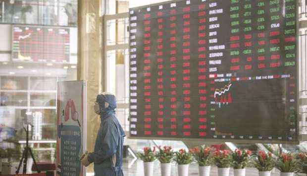A worker wearing a protective suit stands at a temperature screening point in front of an electronic stock board at the Shanghai Stock Exchange. The Composite index closed up 2.0% to 3,152.81 points yesterday.