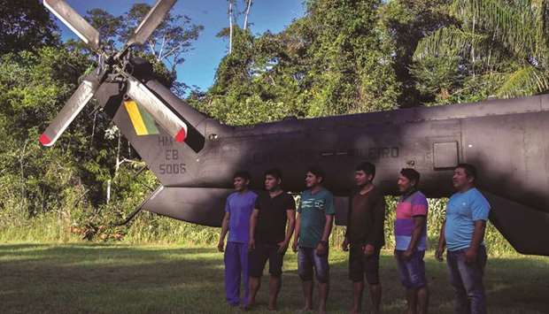 Indigenous Yeu2019kuana pose in front of a helicopter at the 5th Special Frontier Platoon in Auari, Roraima state, Brazil, amid the coronavirus pandemic.