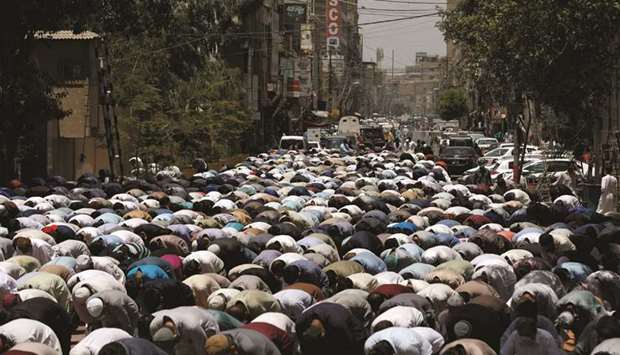 People attend Friday prayers yesterday along a road in Karachi, after the authorities re-imposed lockdowns in selected areas in an effort to stop the spread of the coronavirus disease.