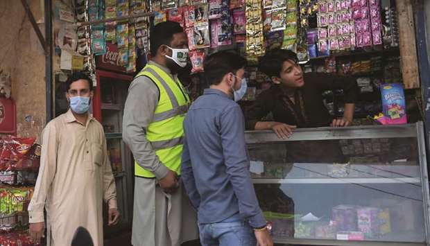 Members of Prime Minister Imran Khanu2019s Corona Relief Tiger Force speak with a shopkeeper as part of a coronavirus awareness campaign in Rawalpindi.