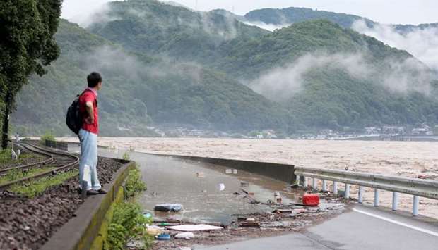 A man looks at the overflowing kuma river caused by heavy rain in Yatsushiro, Kumamoto prefecture