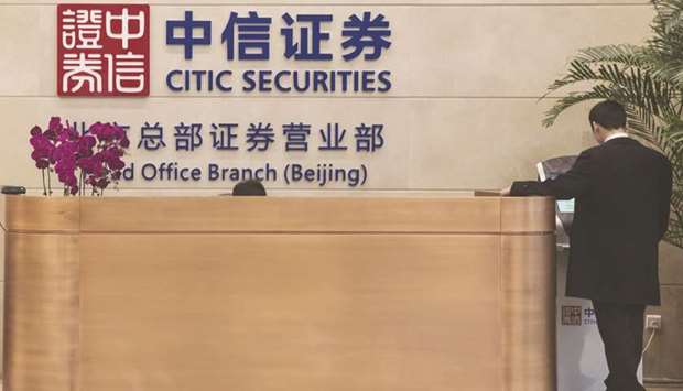 A man stands next to the reception desk at the Citic Securities headquarters in Beijing. Citic Group, the parent of Chinau2019s largest broker Citic Securities Co, will act as the main buyer of a stake in CSC Financial Co, the nationu2019s No 2, according to people familiar with the matter.