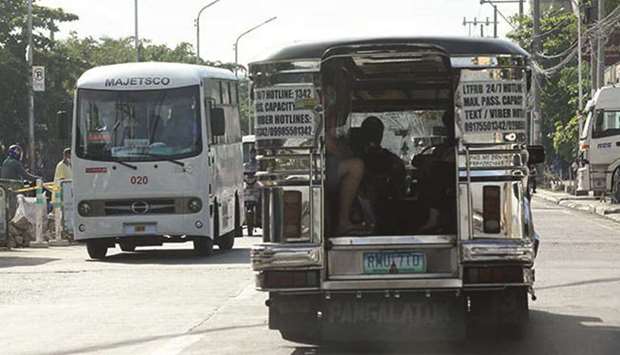 A traditional jeepney plying the Monumento-Malabon route runs near a modernised jeepney heading in the opposite direction on an unidentified road in Malabon City.