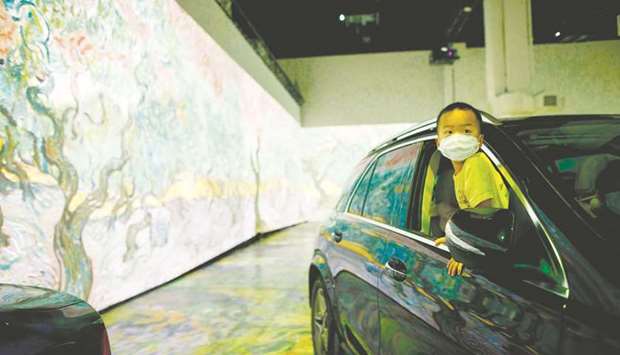 Tyler Tsang, 4, peeks out of the car as he experiences a drive-in immersive Vincent Van Gogh art exhibit in Toronto on Friday.