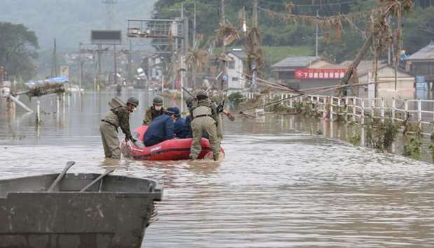 Japan Self-Defense Forces and police officers handle an inflatable boat to join rescue operations at a nursing home following heavy rain in Kuma village, Kumamoto prefecture