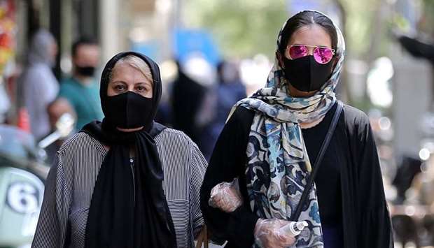 Iranian women wearing protective masks due to the Covid-19 pandemic, walk along a street in the capital Tehran