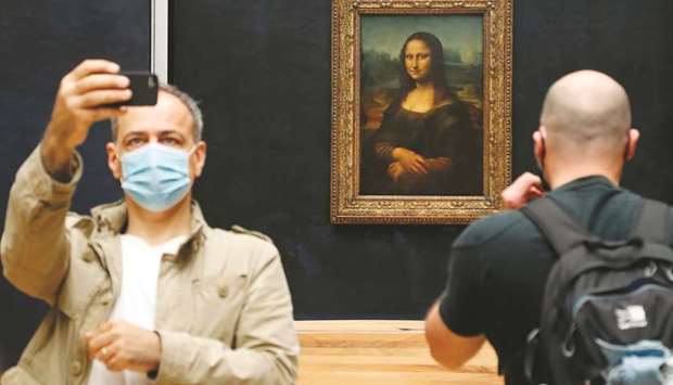 A visitor wearing a face mask takes a selfie in front of Leonardo da Vinciu2019s masterpiece u2018Mona Lisau2019 at the Louvre Museum in Paris yesterday.