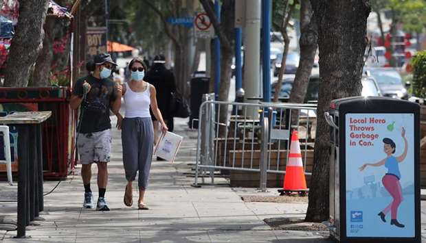 GETTING IN ON THE ACT: A couple walk along Santa Monica Boulevard last Thursday in West Hollywood, California. Los Angeles County Sheriffu2019s deputies will issue citations for not wearing masks in public.