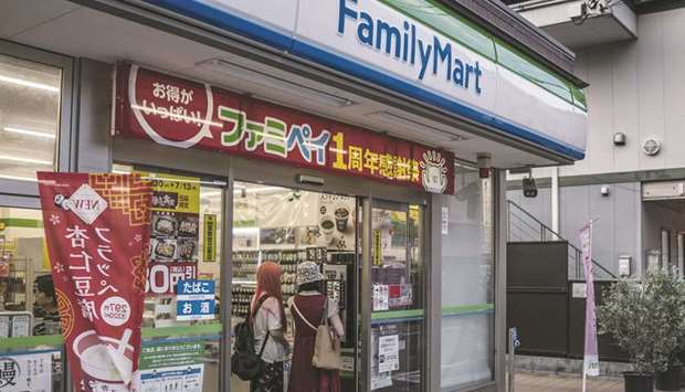 Customers make coffee at a FamilyMart convenience store in Tokyo. Itochu Corp is planning to take full control of convenience-store chain FamilyMart through a tender offer, the retailer said yesterday.