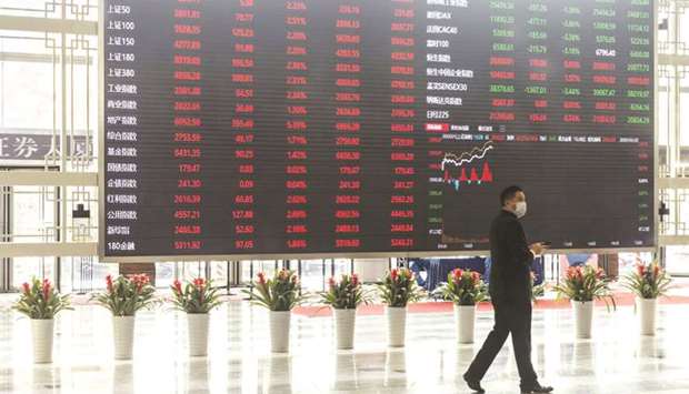 A man wearing a protective mask walks past an electronic stock board at the Shanghai Stock Exchange. The Shanghai index rallied 1.4% to 3,450.59 points yesterday as data showed a pick-up in inflation that indicates the worldu2019s number-two economy continues to improve.