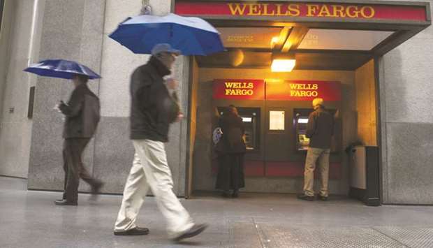 Pedestrians walk in front of Wells Fargo & Co headquarters in San Francisco. Pressure to dramatically reduce costs is coming to a head inside the bank, prompting executives to draft plans that may ultimately eliminate tens of thousands of positions, people with knowledge of the confidential talks said.
