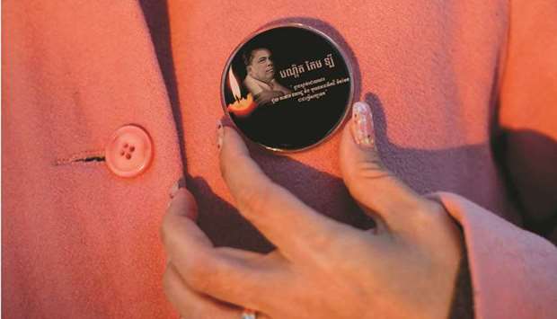 Bou Rachna touches a badge with the photo of her late husband, the slain Cambodian analyst Kem Ley, at the Wat Buddharangsi Buddhist Temple in Melbourne.