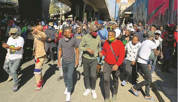 Stick-wielding protesters march through the streets as violence following the jailing of former South African president Jacob Zuma spread to the countryu2019s main economic hub in Johannesburg, yesterday.