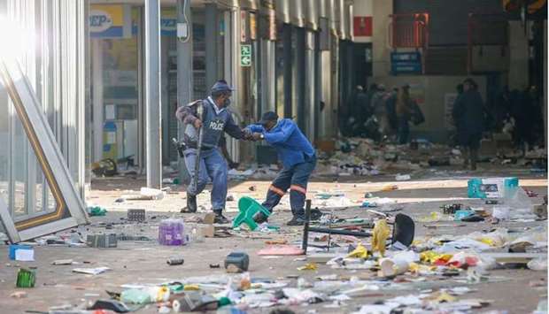 A member of the South African Police Services (SAPS) arrests a looter inside the Lotsoho Mall in Katlehong township, East of Johannesburg
