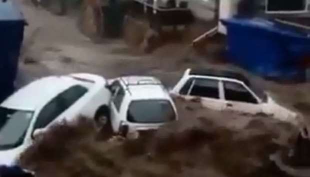 An image grab from a video posted on social media shows vehicles parked in a town being swept away in the flood water