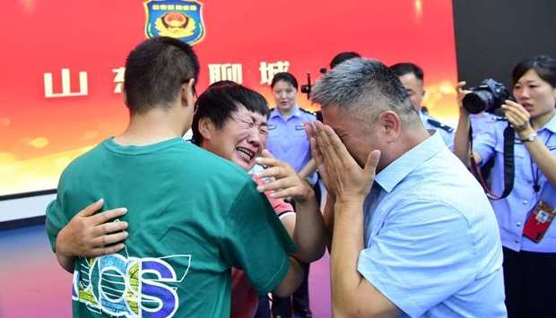 Guo Gangtang, 51, and his wife reunite with their son Guo Xinzhen, who was abducted 24 years ago at the age of 2, at a family reunion arranged by the police, in Liaocheng, Shandong province, China on July 11.  China Daily via REUTERS
