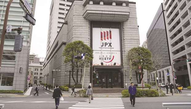 Pedestrians walk by the Tokyo Stock Exchange building. The Nikkei 225 closed down 1.0% to 28,003.08 points yesterday.