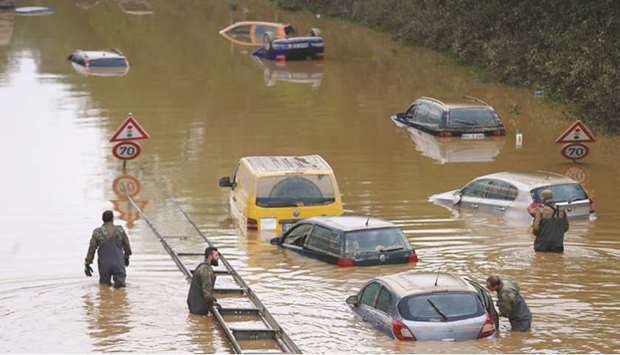 Members of the Bundeswehr forces, surrounded by partially submerged cars, wade through the flood water following heavy rainfalls in Erftstadt-Blessem, Germany, yesterday. (Reuters)