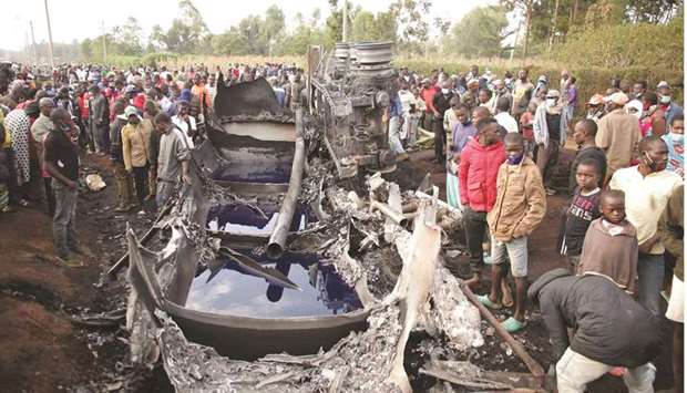 People stand next to a burnt out petrol tanker that burst into flames when it overturned in western Kenya, some 315km northwest of Nairobi, on the highway between Kisumu and the border with Uganda, yesterday.