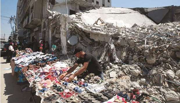 A Palestinian sells shoes on a stall near the rubble of his old shoe store that has been destroyed in an Israeli air strike, ahead of Eid al-Adha holiday, in Gaza City.