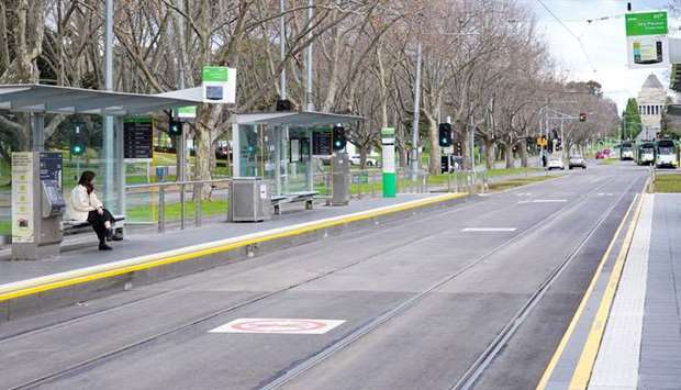 A lone passenger sits at a tram stop on a mostly-empty city centre street on the first day of a lockdown as the state of Victoria looks to curb the spread of a coronavirus disease (COVID-19) outbreak in Melbourne, Australia. (REUTERS)