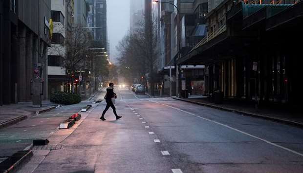 A pedestrian crosses an empty street in the deserted city centre at morning commute hour during a lockdown to curb the spread of a coronavirus disease (Covid-19) outbreak in Sydney, Australia