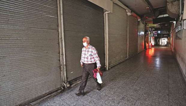An Iranian man wearing a protective face mask walks past shuttered stores at a commercial centre in downtown Tehran, yesterday.