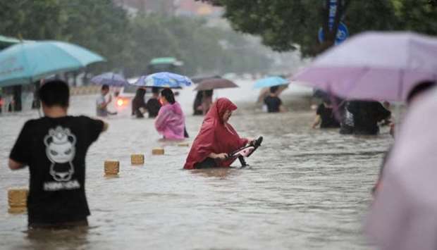 Residents wade through floodwaters on a flooded road amid heavy rainfall in Zhengzhou, Henan province, China. China Daily via REUTERS