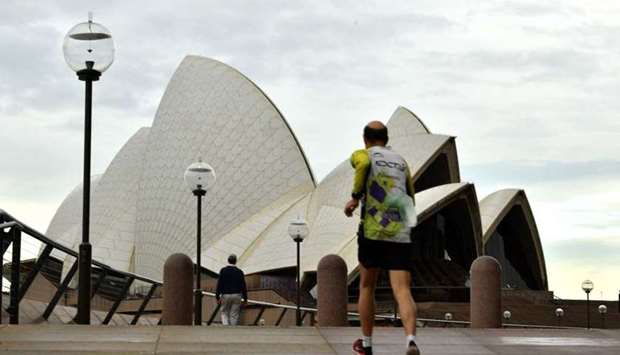 A man jogs towards the iconic Opera House in Sydney on July 23, amid a coronavirus outbreak that state leaders said has become a ,national emergency,.