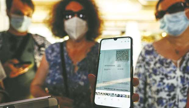 A woman shows her health pass at a restaurant in Mont-Saint-Michel, northwestern France. French cinemas, museums and sports venues have begun asking visitors to furnish proof of coronavirus (Covid-19) vaccination or a negative test as the country, which is in the throes of a fourth wave of infections, rolled out a controversial vaccine passport system