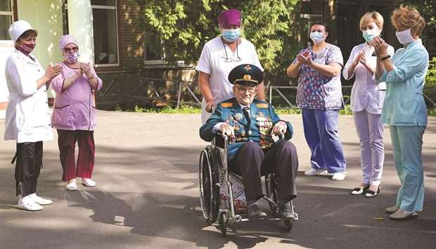 World War Two veteran Nikolay Bagayev (right) is applauded as he leaves hospital after being treated for the coronavirus disease and discharged, in Korolyov, Russia.