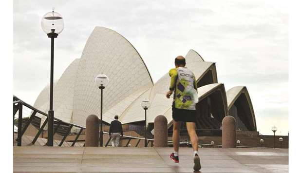 A man jogs towards the iconic Opera House in Sydney amid a coronavirus outbreak that state leaders s