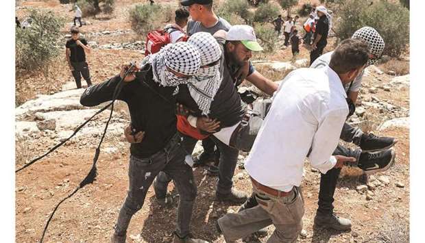Palestinian protesters carry away an injured man during confrontations with security forces in the town of Beita, near the occupied West Bank city of Nablus, yesterday, after a protest against the newly-established wildcat settler outpost of Eviatar.