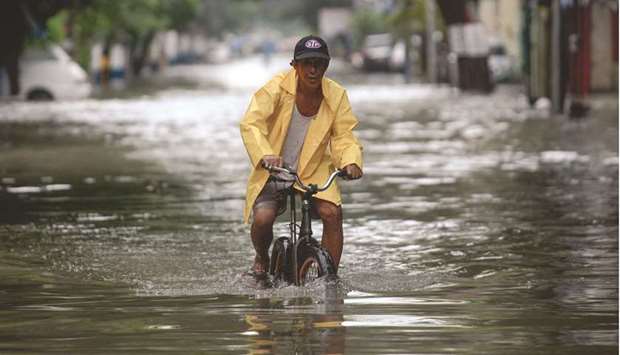 A man on a bicycle wades through a flooded street in Manila.