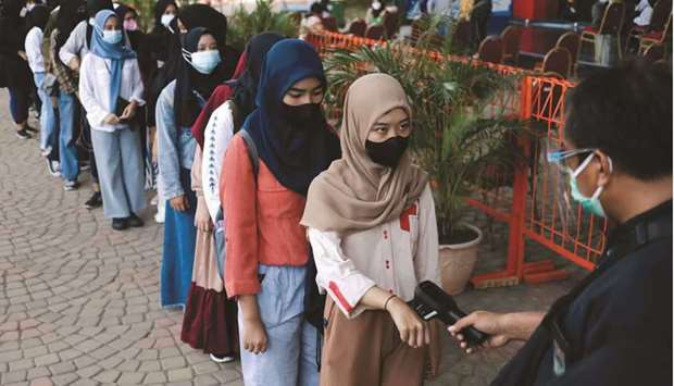 A girl has her temperature checked as she arrives to receive Chinau2019s Sinovac Biotech vaccine in Jakarta.