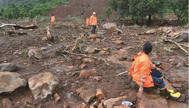 A National Disaster Response Force (NDRF) personnel rests as others search for victims after a landslide at Taliye.