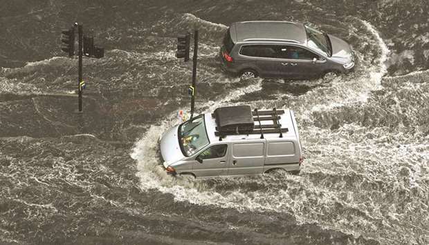 Vehicles drive through a flooded road in The Nine Elms district of London during heavy rains yesterday.